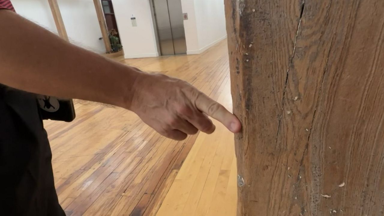 Nick Piornack examining an indent in the wood pillar made by a loom